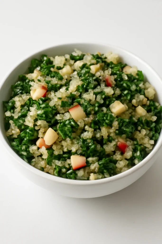 Fluffy cooked quinoa mixed with kale and apples in a bowl