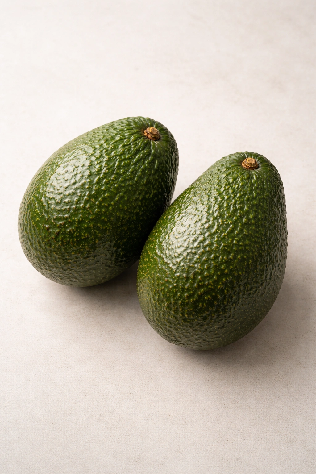 Two whole avocados on neutral background signifying dietary guidance