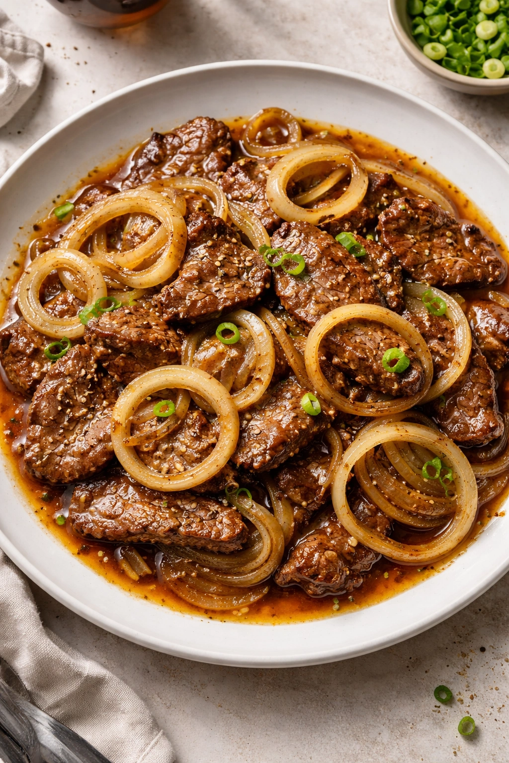 Beef bistek tagalog with onions in tangy sauce on plate