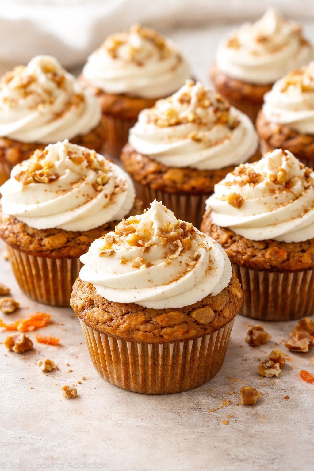 Carrot cake muffins with cream cheese frosting on light surface