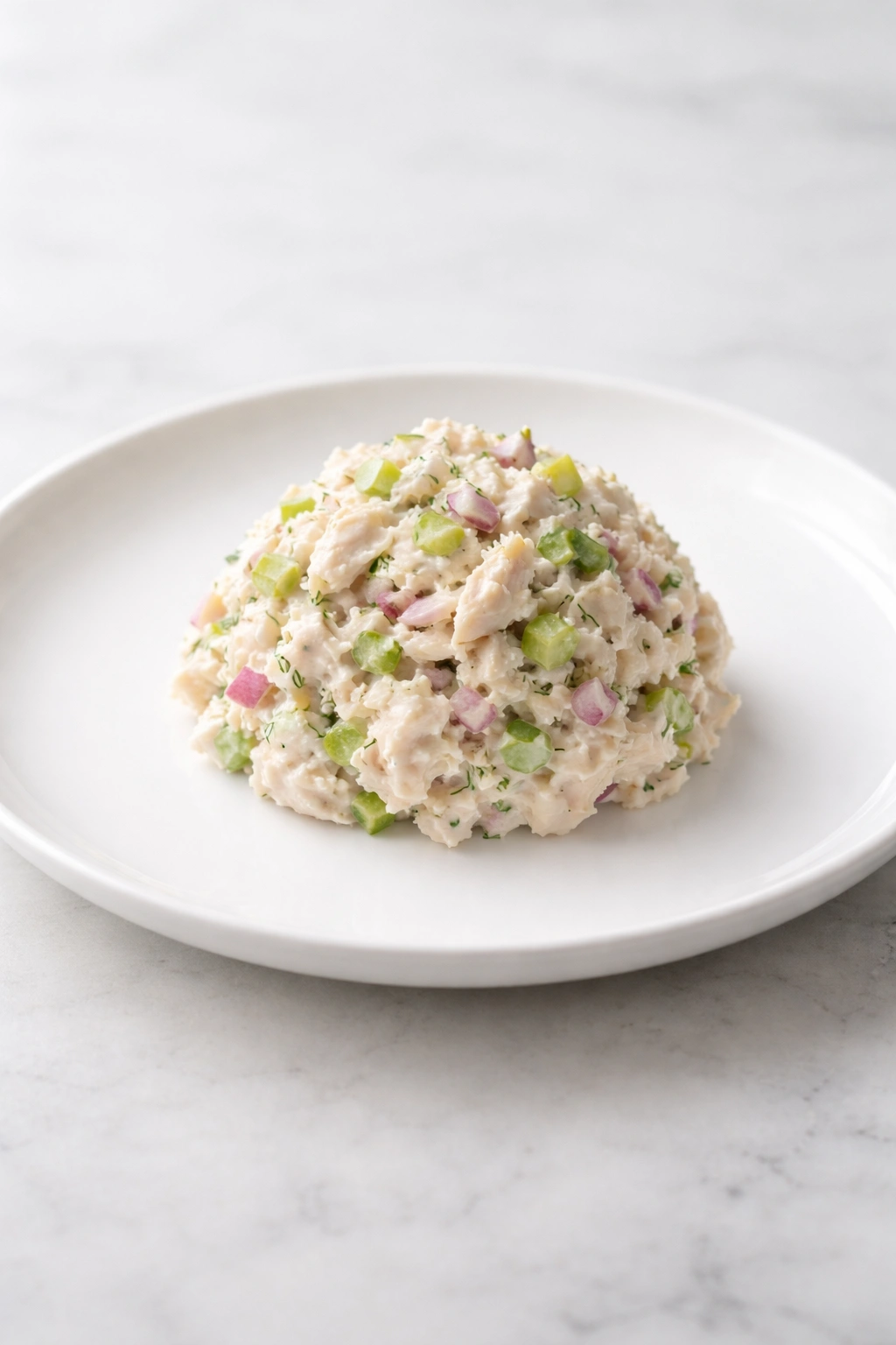 Chicken salad plated simply on a white plate