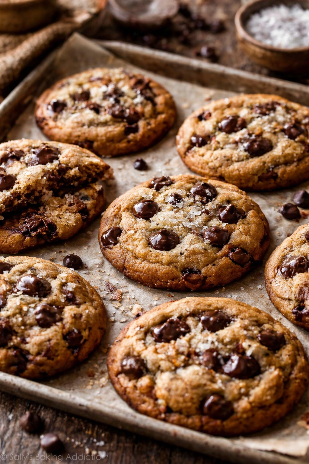 Close-up of soft chocolate chip cookies showing browned butter edges and salt crystals on a rustic board