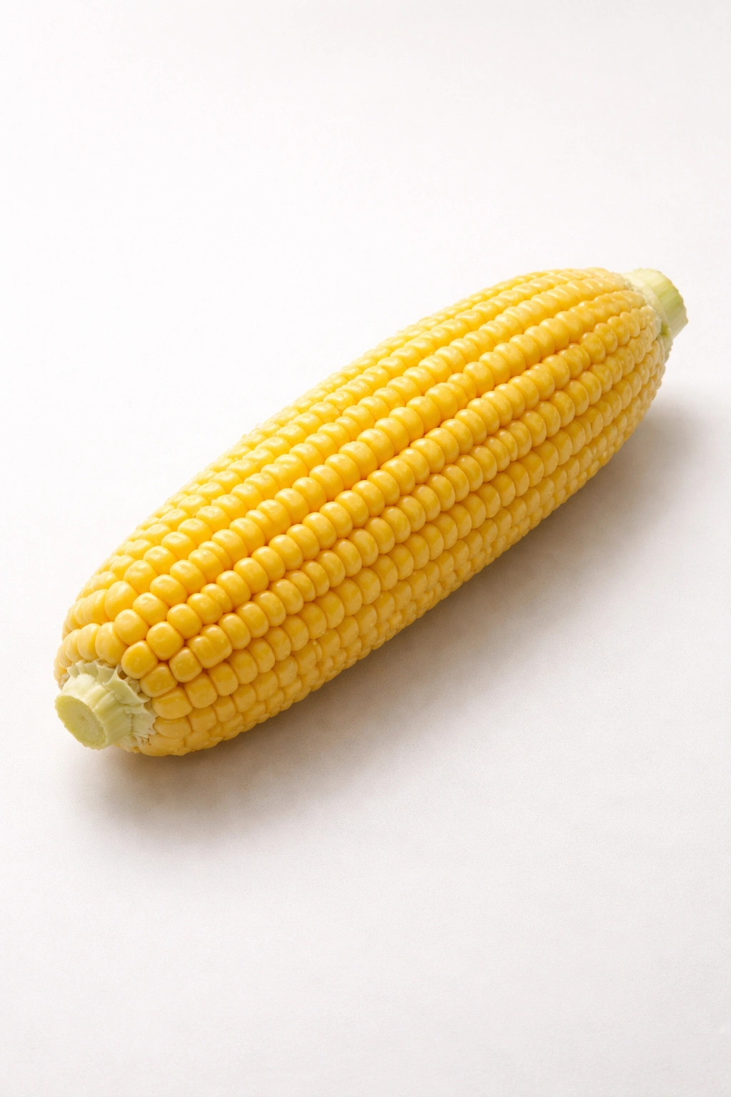 Single ear of corn on a clean neutral surface.