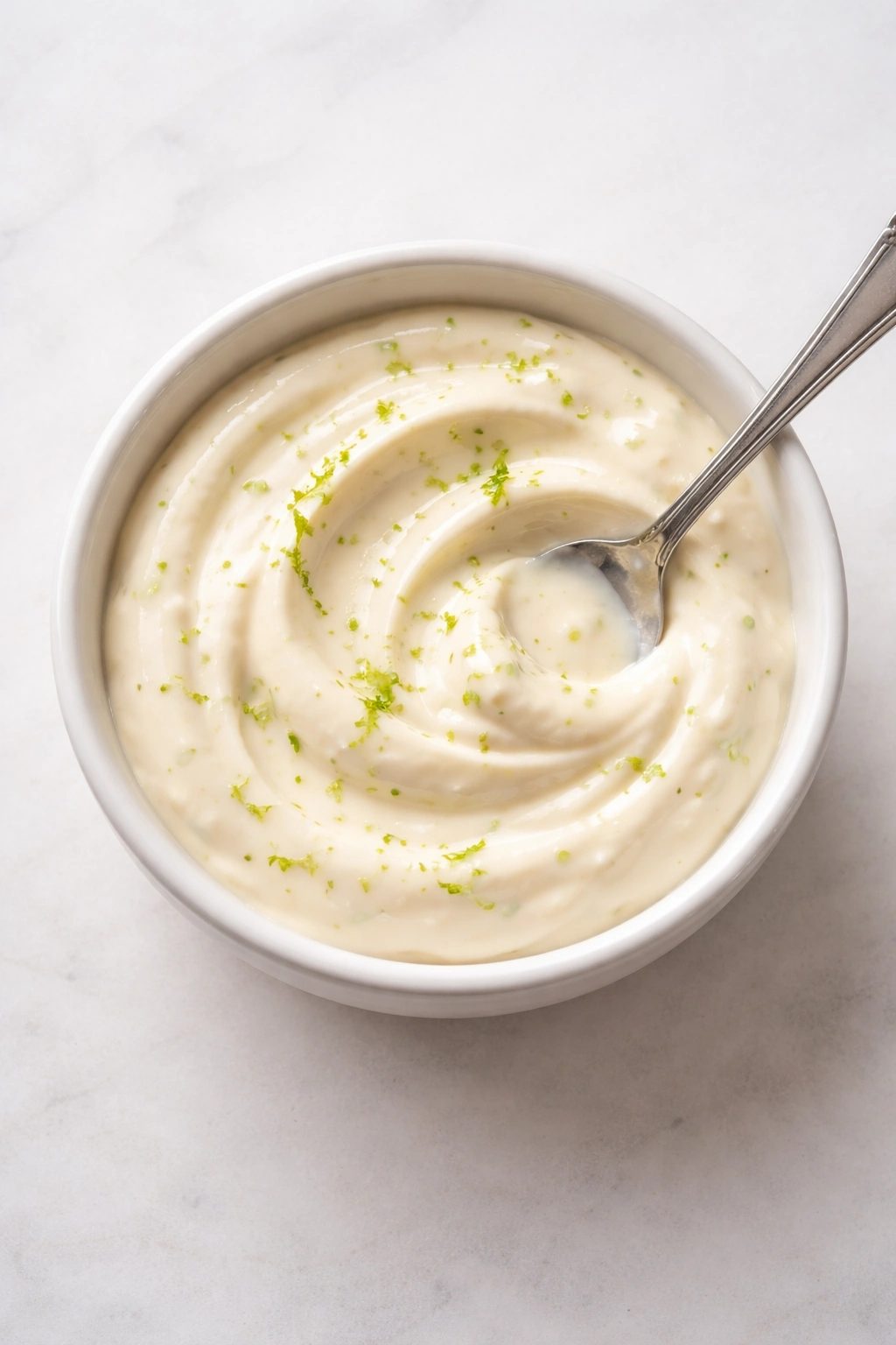 Creamy elote coating in a bowl with lime zest