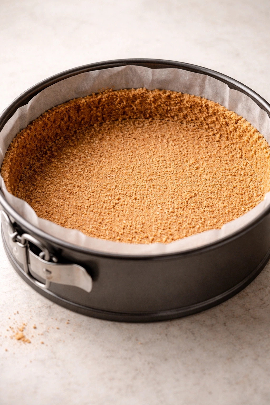 Graham cracker crust pressed into springform pan with parchment edge