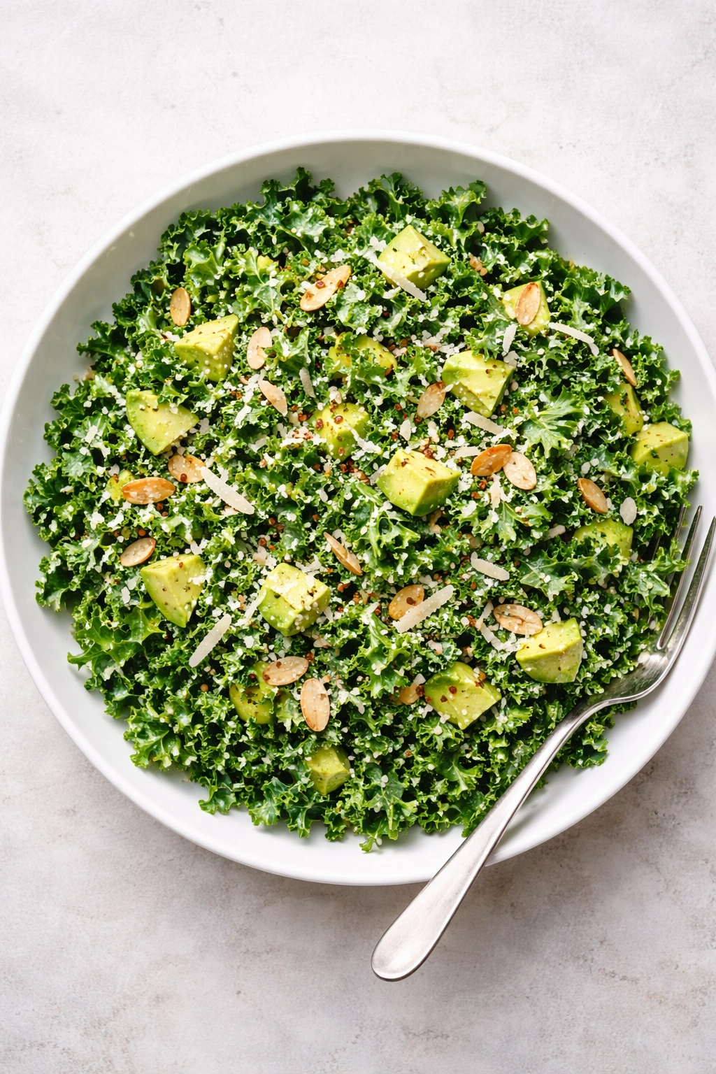 Top-down view of a simple kale salad on a white plate