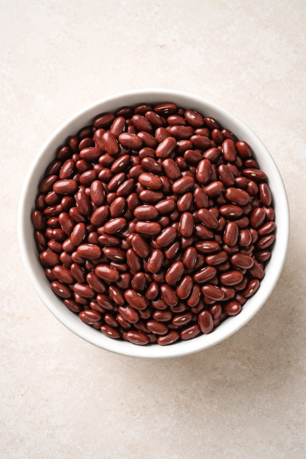 Top-down view of dried kidney beans in a plain bowl on a neutral surface