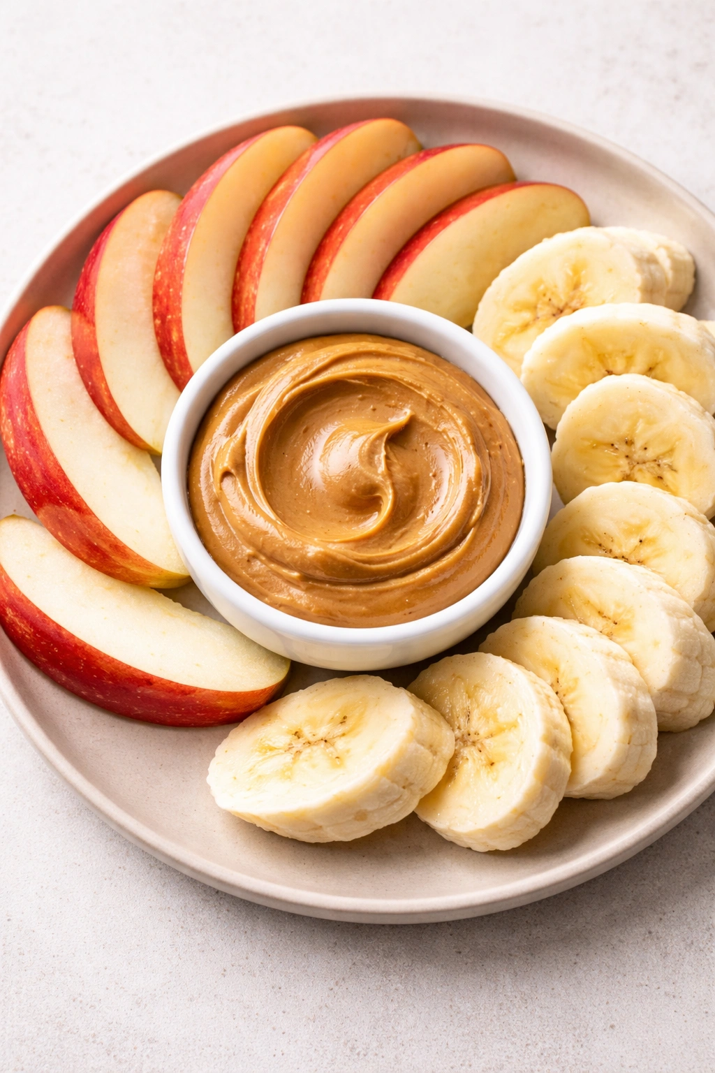 Apple slices with peanut butter on a neutral plate