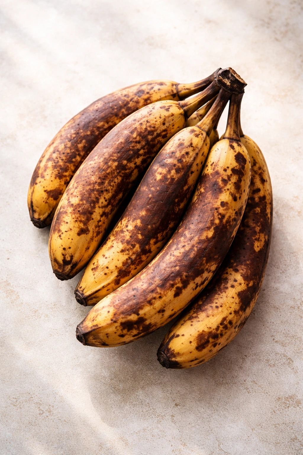 Overripe bananas with brown spots on light background