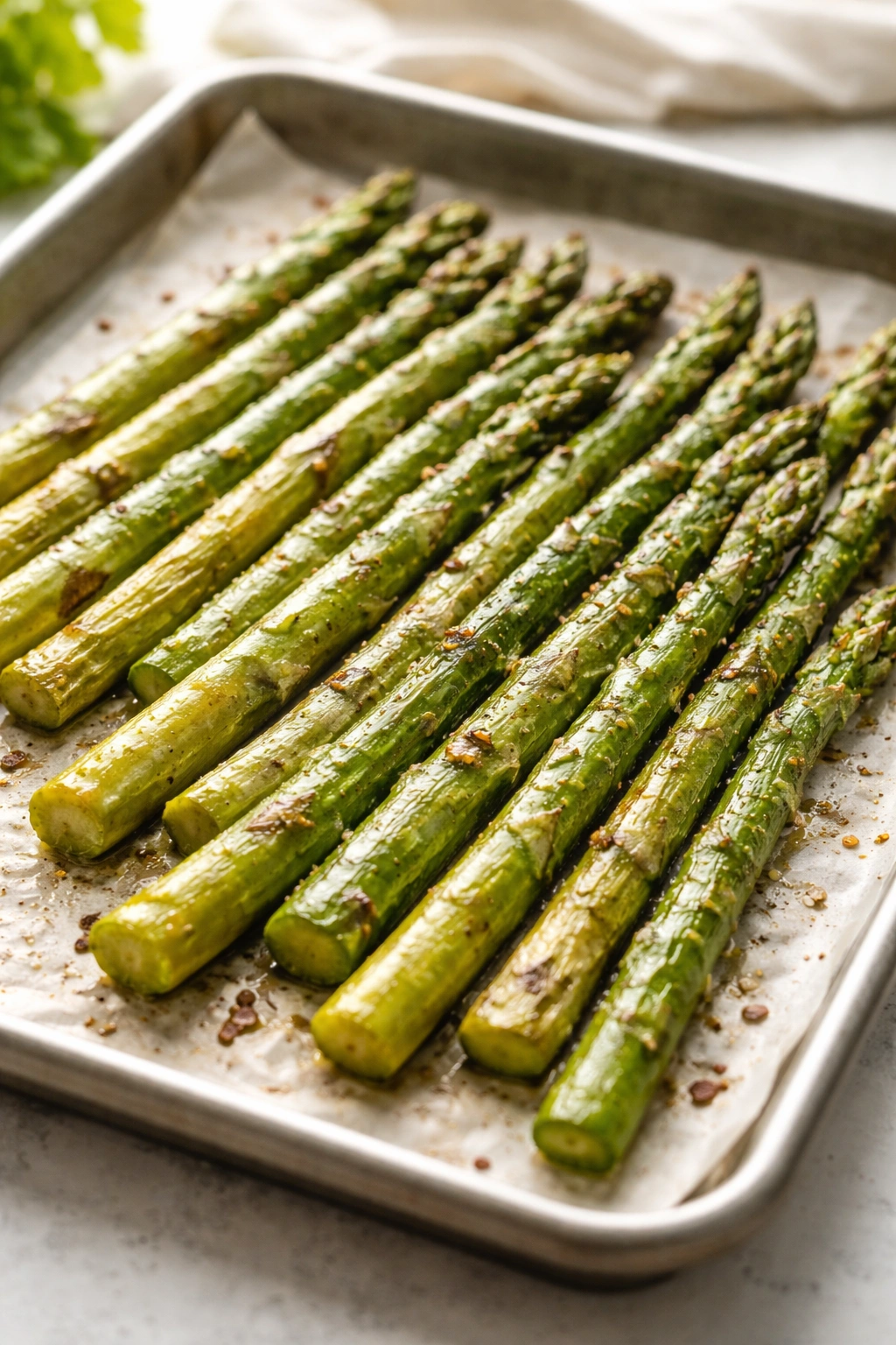 Roasted asparagus spears on parchment with olive oil glaze