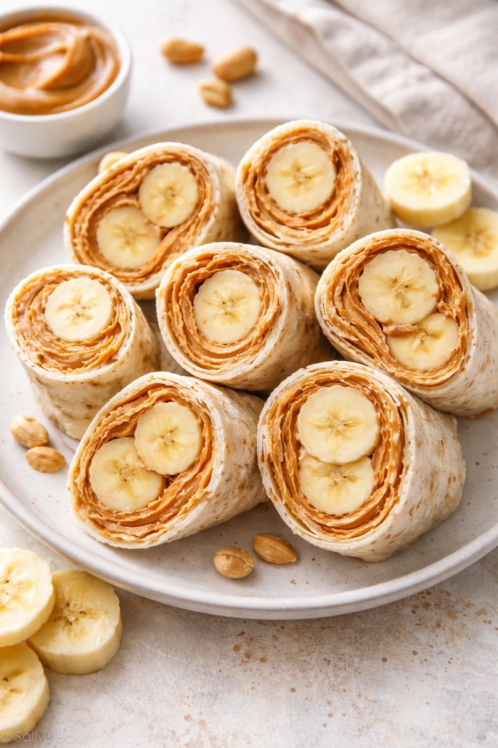 Top-down view of peanut butter and banana roll-ups sliced in half on a plate