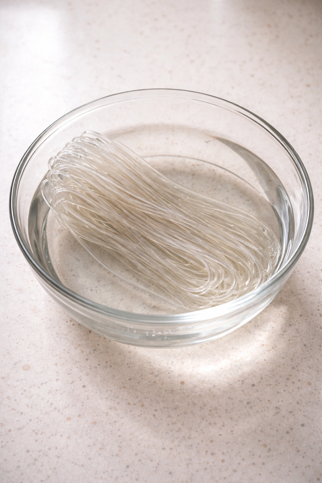 Translucent glass noodles soaking in a glass bowl