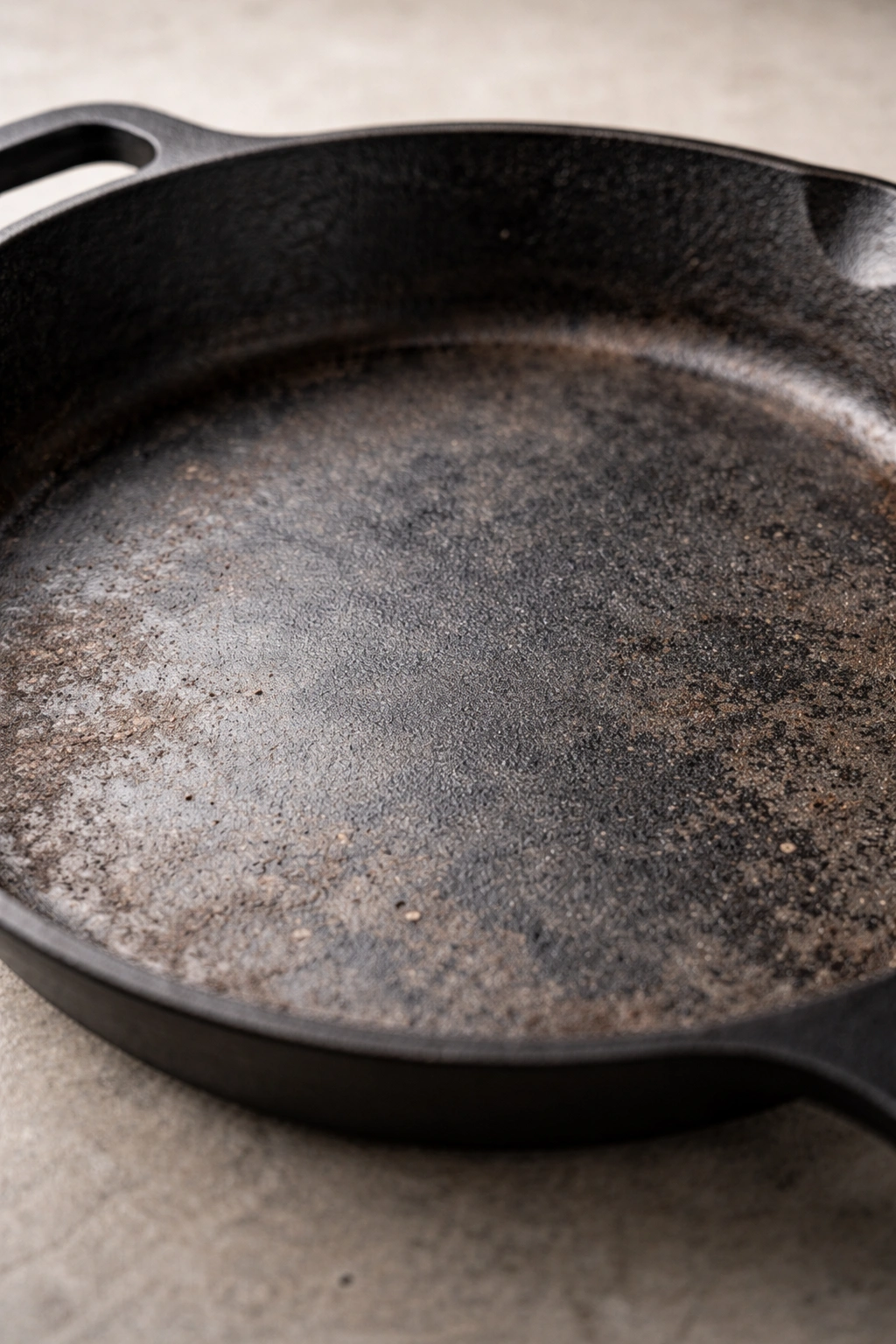 Bare dull cast iron skillet surface lacking seasoning