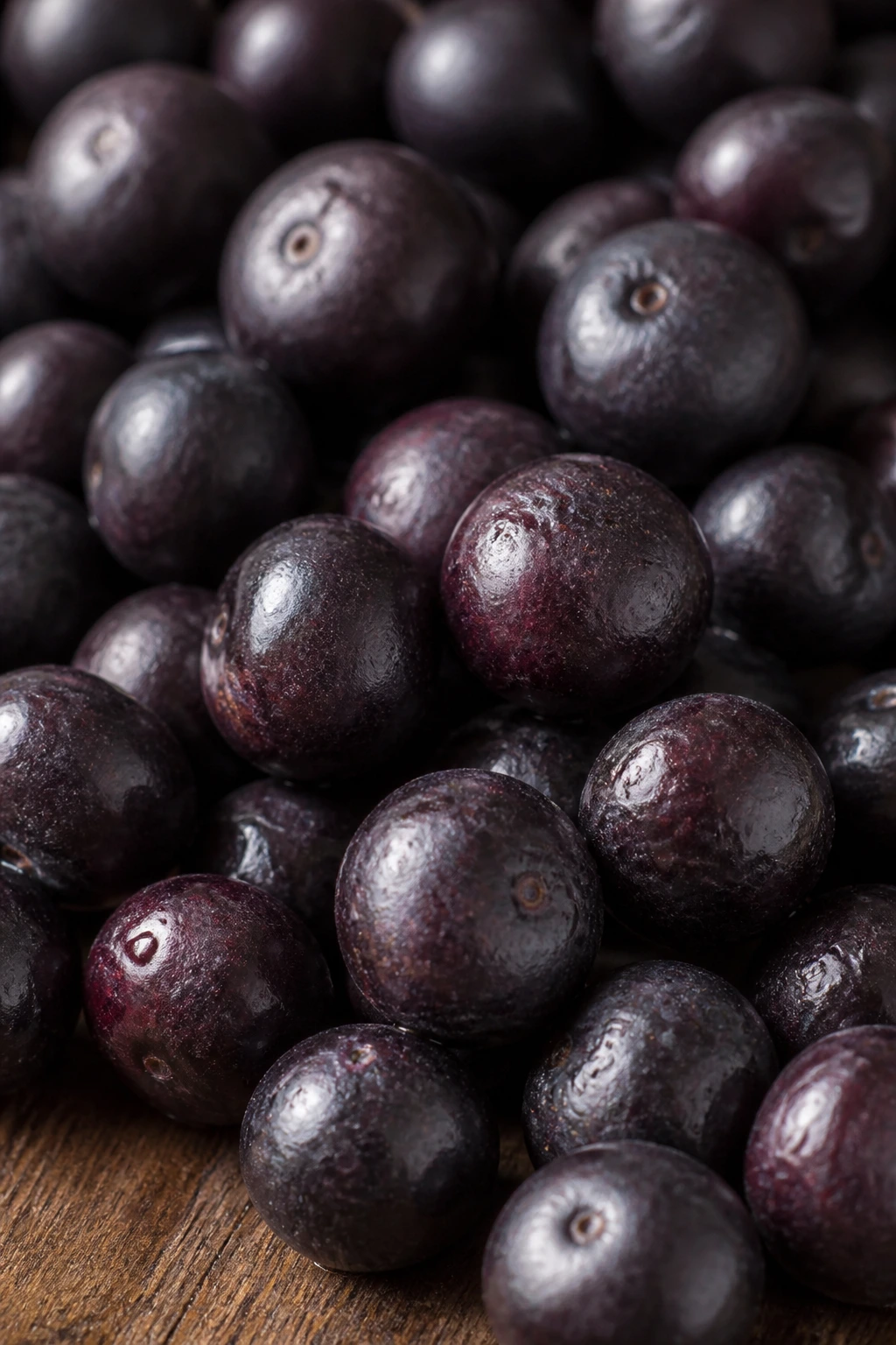 Close-up of fresh acai berries filling the frame on a wooden table