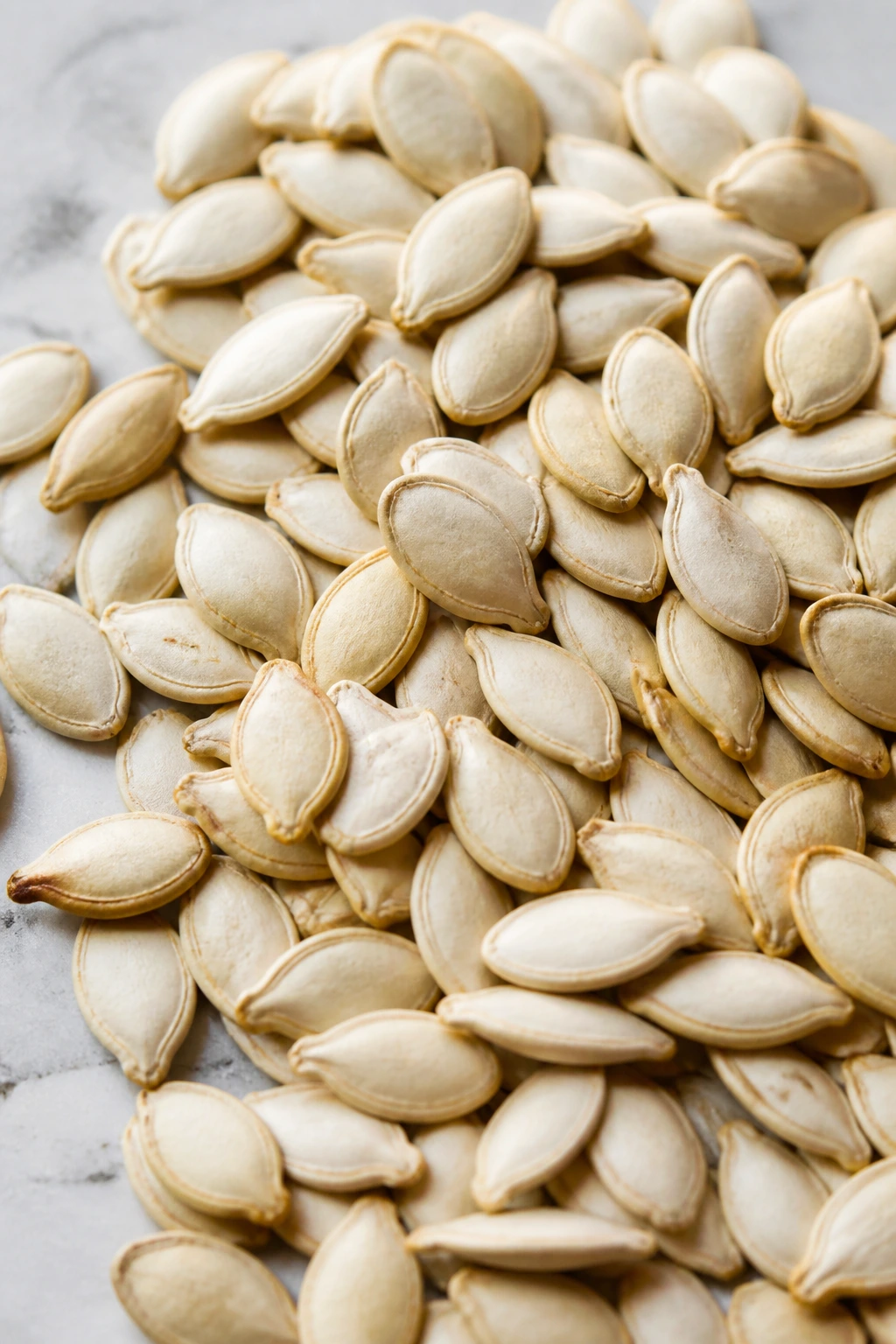 Close-up of raw acorn squash seeds on light surface