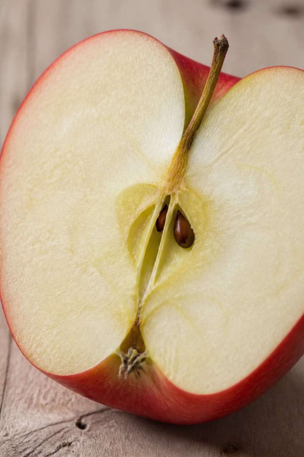 Halved apple showing crisp flesh and seeds filling the frame on wood