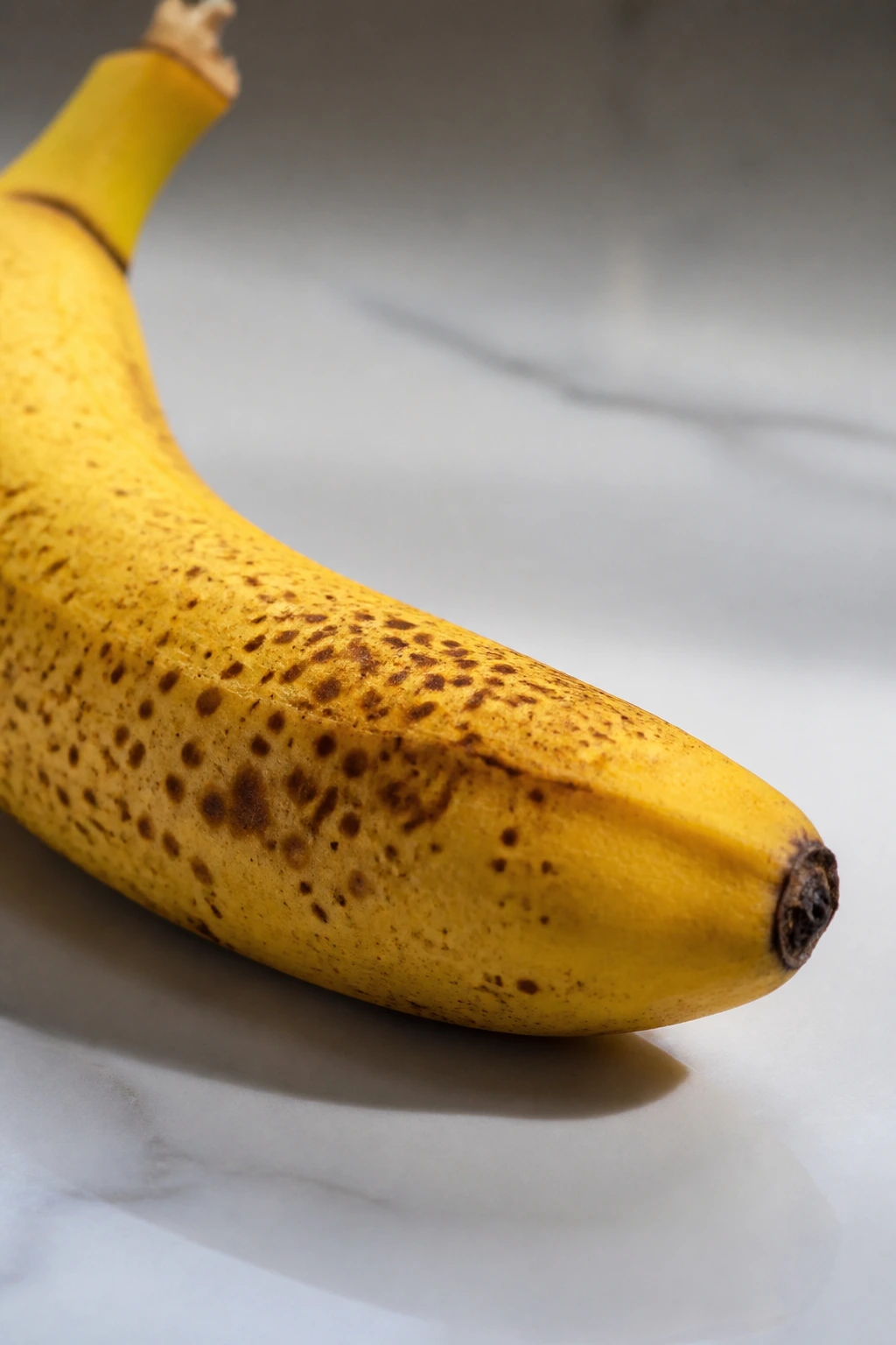 Close-up of a banana on a plain surface in soft daylight