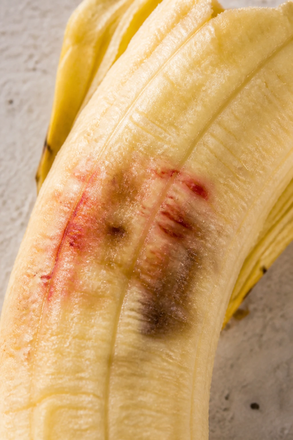Is It Safe To Eat Bananas With Red Spots? Here are the Facts. 3 Peeled banana showing brown bruising near red spots on interior flesh
