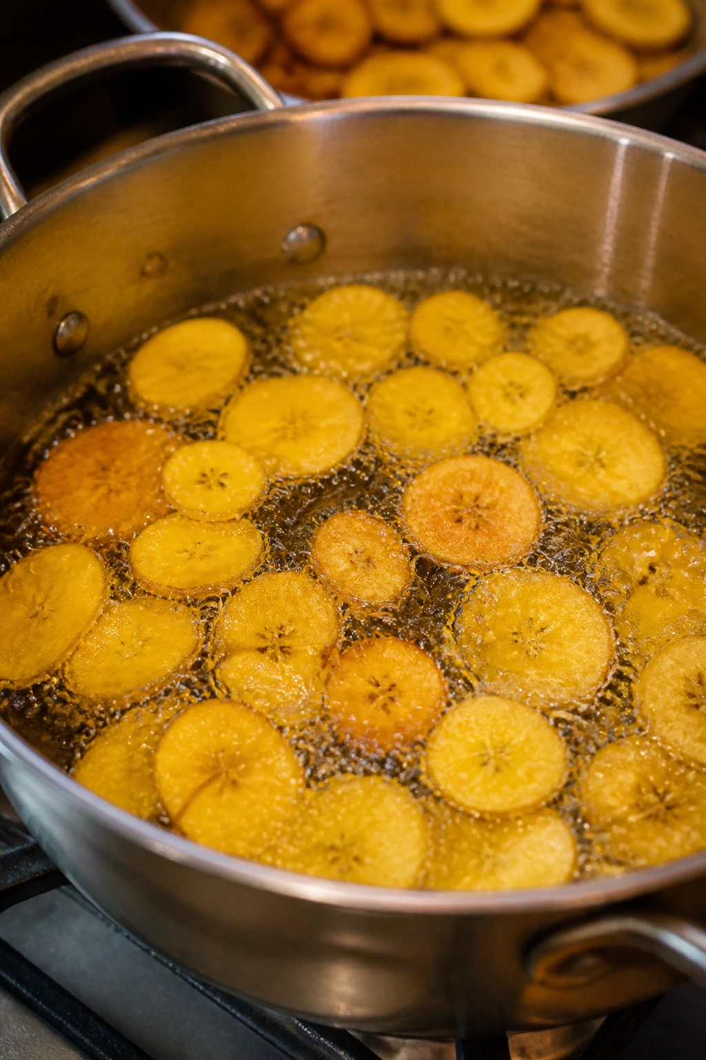 How to Make Banana Chips Commercially: A Complete Guide 4 Banana chips frying in hot oil in a pot.