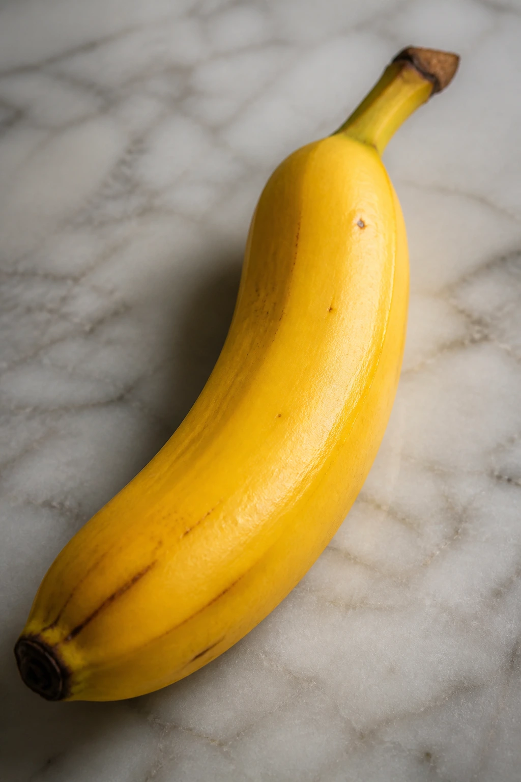 Glossy banana close-up on a neutral kitchen surface.