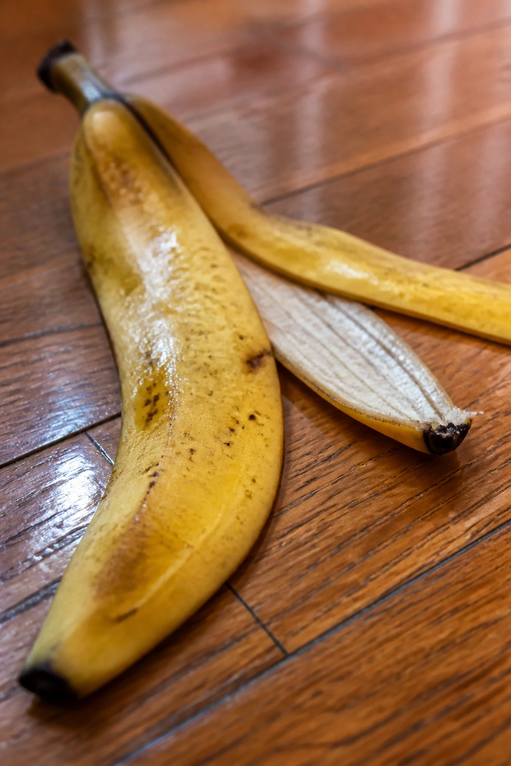 Close-up of overlapping banana peels on wooden floor.