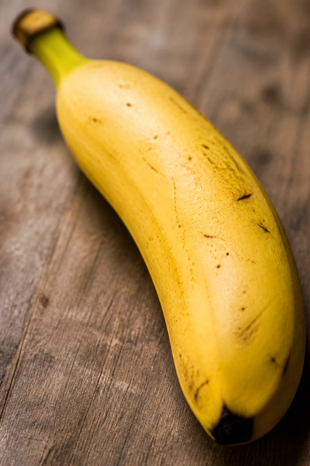 Close-up of a ripe banana on a wooden surface.