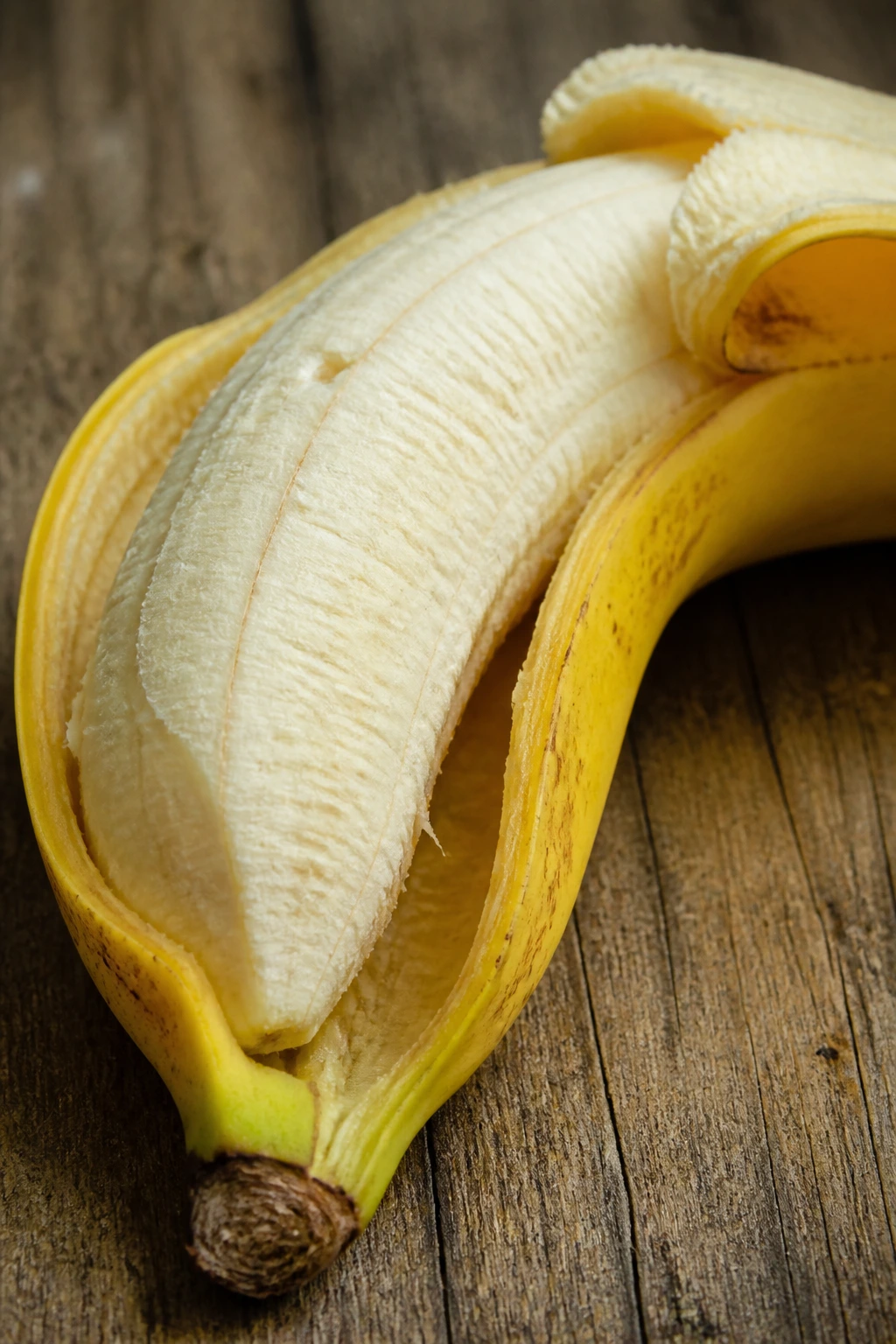 Can Guinea Pigs Eat Bananas And Banana Peel? 6 Close-up of a banana with its peel partially attached on a wooden surface