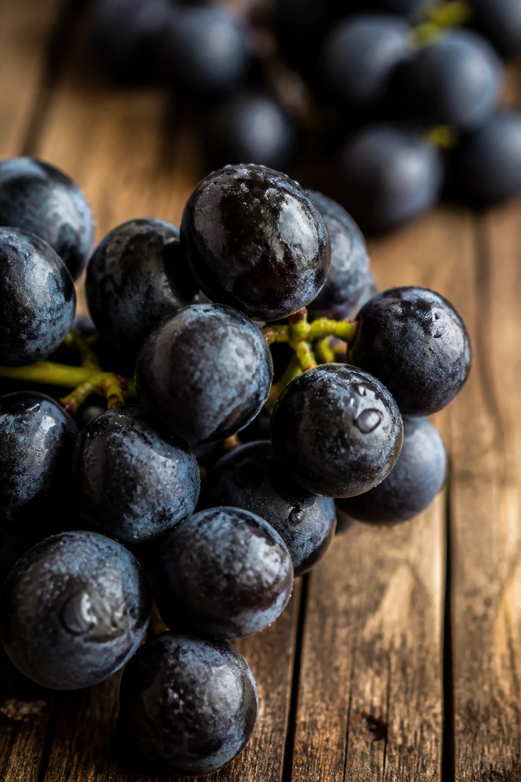 Firm-skinned black grapes filling frame on wooden surface in morning light