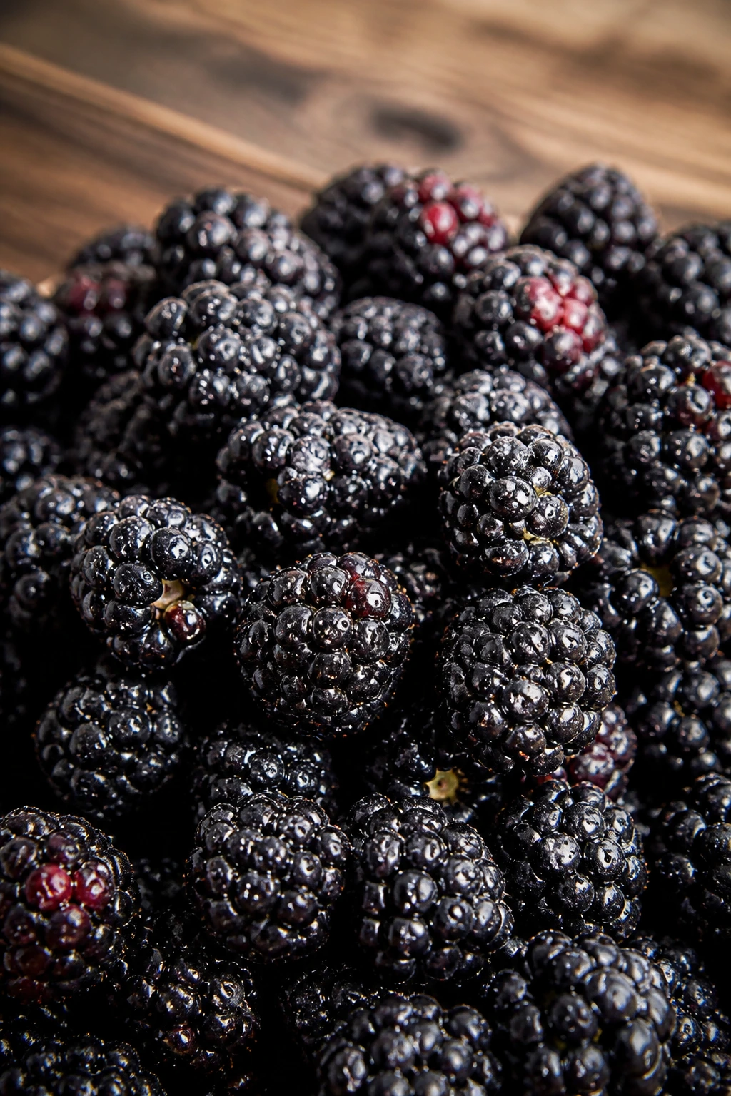 Are Blackberries Good For Your Skin? All You Need To Know 2 Dewy blackberry cluster filling the frame on wood