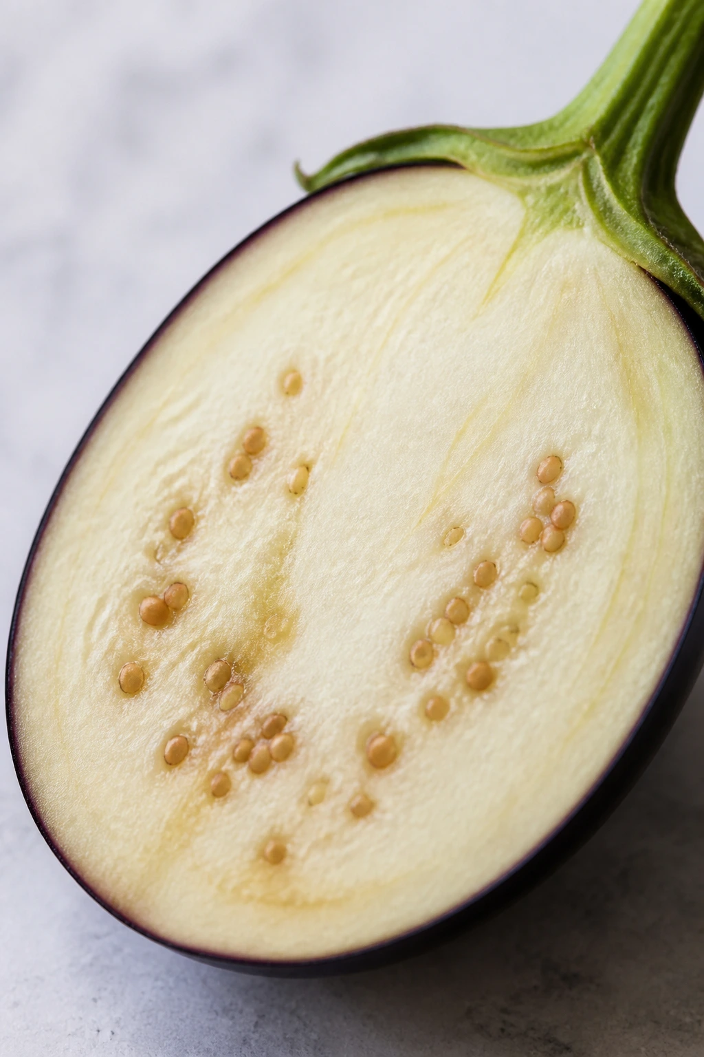 12 Surprising Health Benefits of Garden Egg Fruit 5 Half of a garden egg fruit showing purple skin and pale interior, filling the frame.