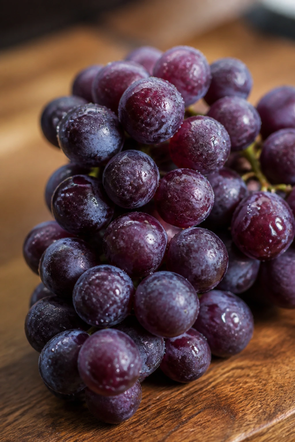 10 Benefits Of Eating Grapes At Night For Weight Loss 2 Close-up of glossy purple grapes on wood with soft kitchen lighting.