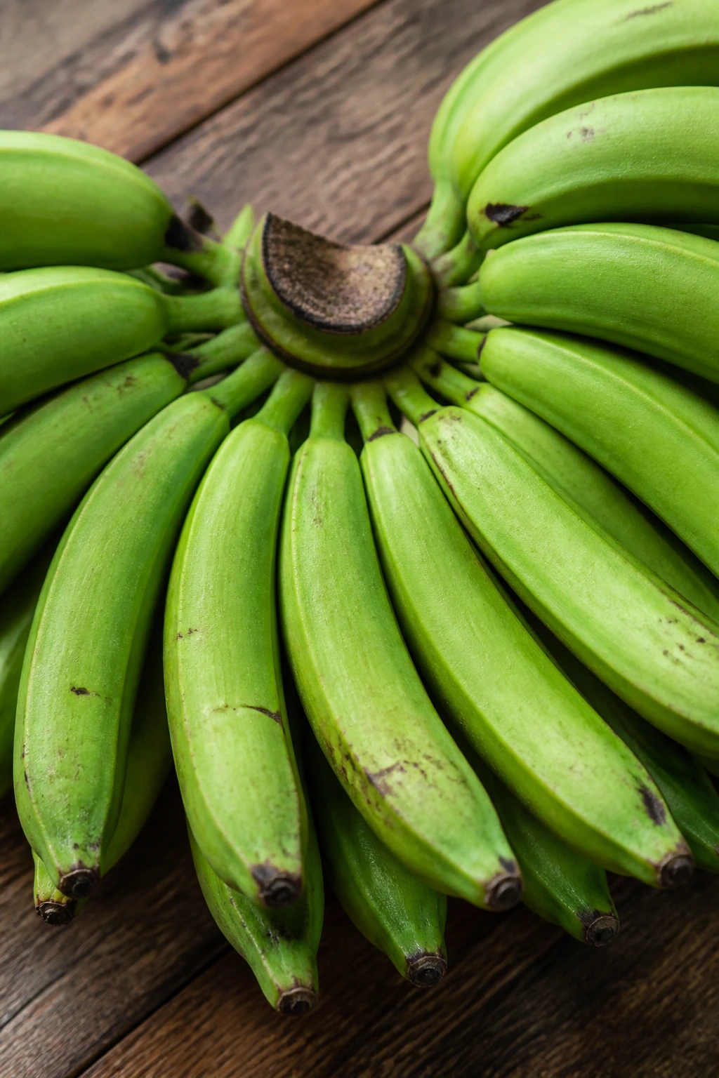 IBS Relief: Are Bananas Good For IBS? 2 Green unripe bananas clustered on a wooden surface
