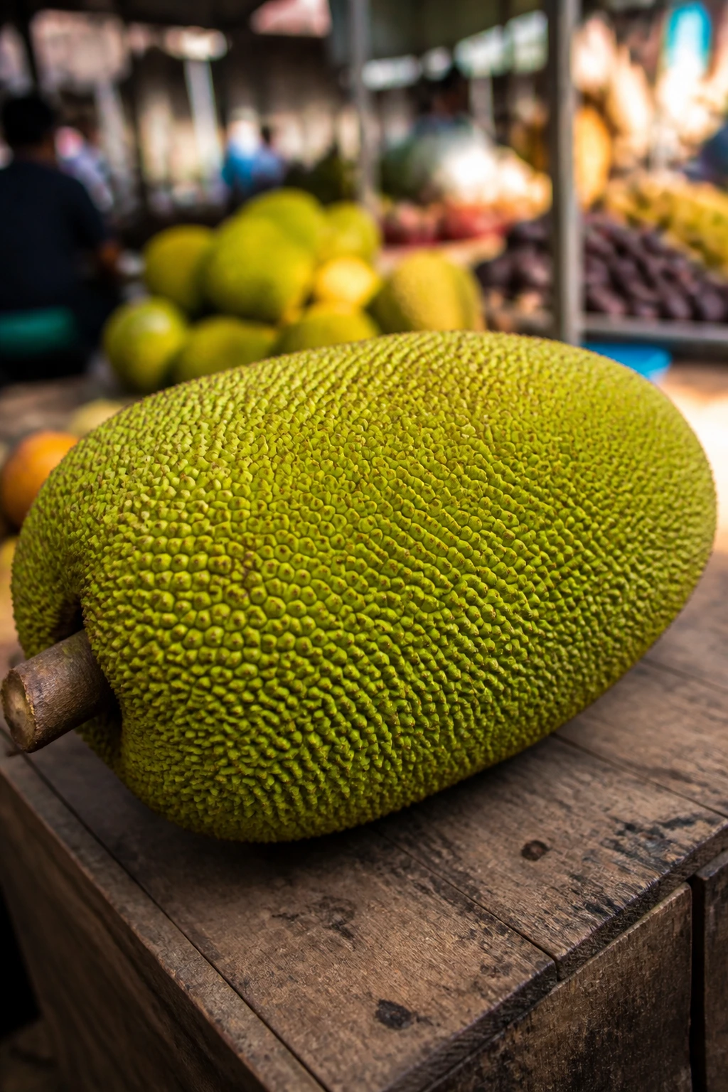 Ripe jackfruit on wooden table with market blur