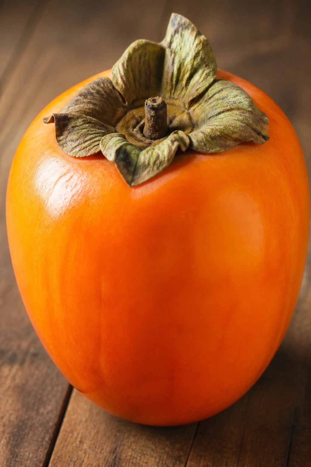 American vs Japanese Persimmon: What's The Difference? 2 Close-up of a single Japanese persimmon on wood surface with bright orange flesh