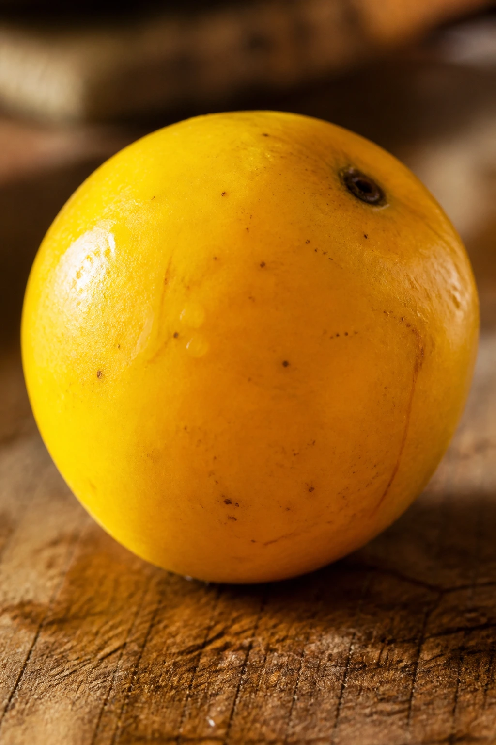 Close-up of bright yellow June plum on wood