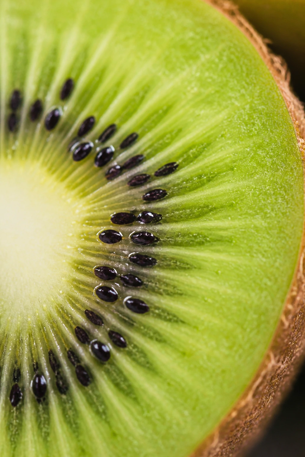 Can You Eat Kiwi Seeds? Is It Safe? What Are The Benefits? 2 Extreme close-up of kiwi seeds in vibrant green flesh of a sliced kiwi