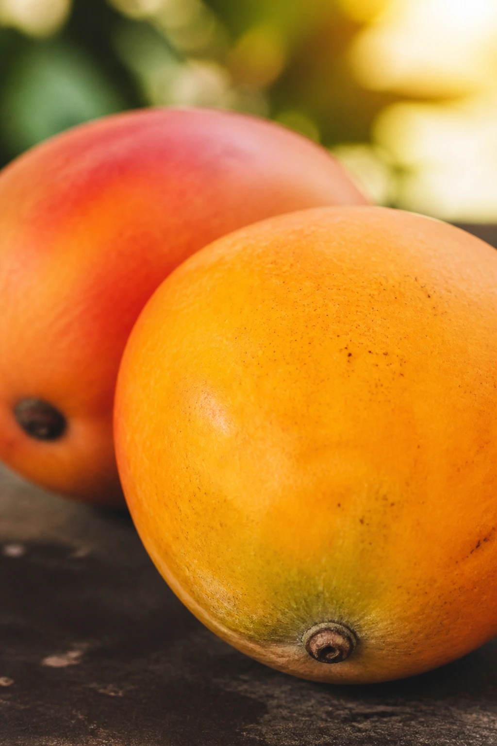 How To Get Mango Out Of Your Teeth & Prevention 5 Two ripe mangoes filling frame in warm outdoor light