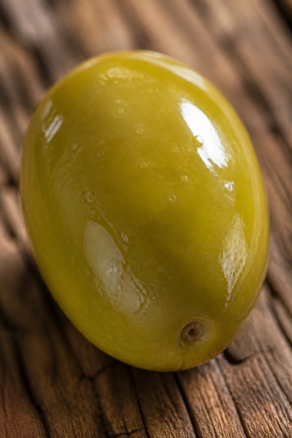 The Definitive Answer: Are Olives Fruits Or Vegetables? 1 Close-up of a single ripe olive on a wooden surface.
