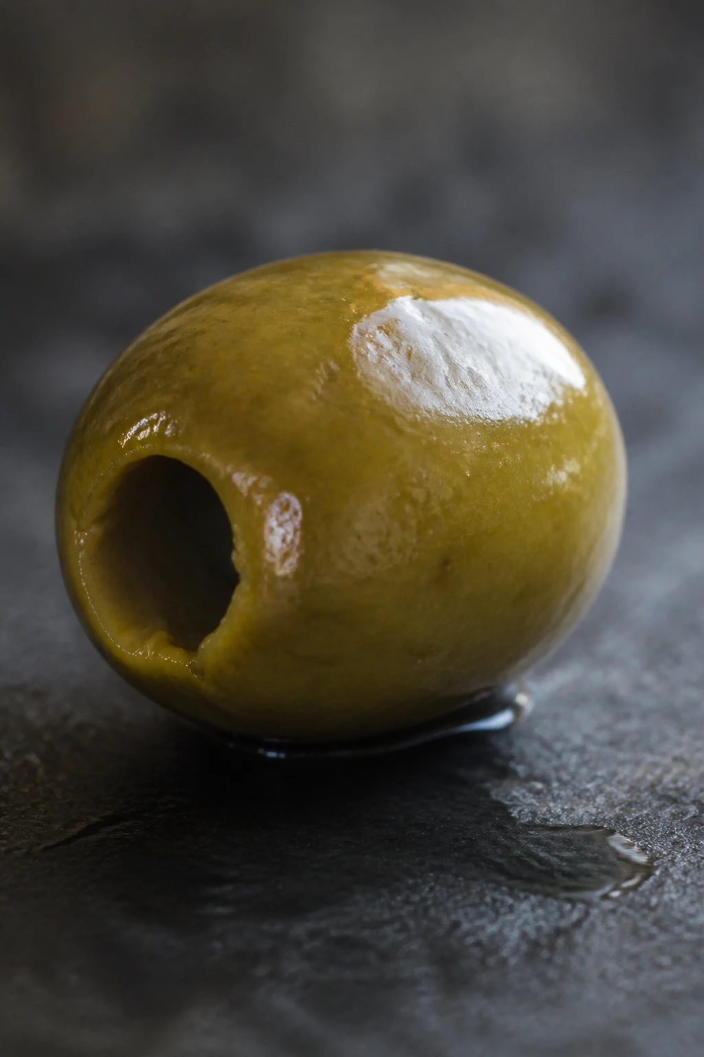 The Definitive Answer: Are Olives Fruits Or Vegetables? 3 Glossy olive with visible oil sheen on a rustic surface.