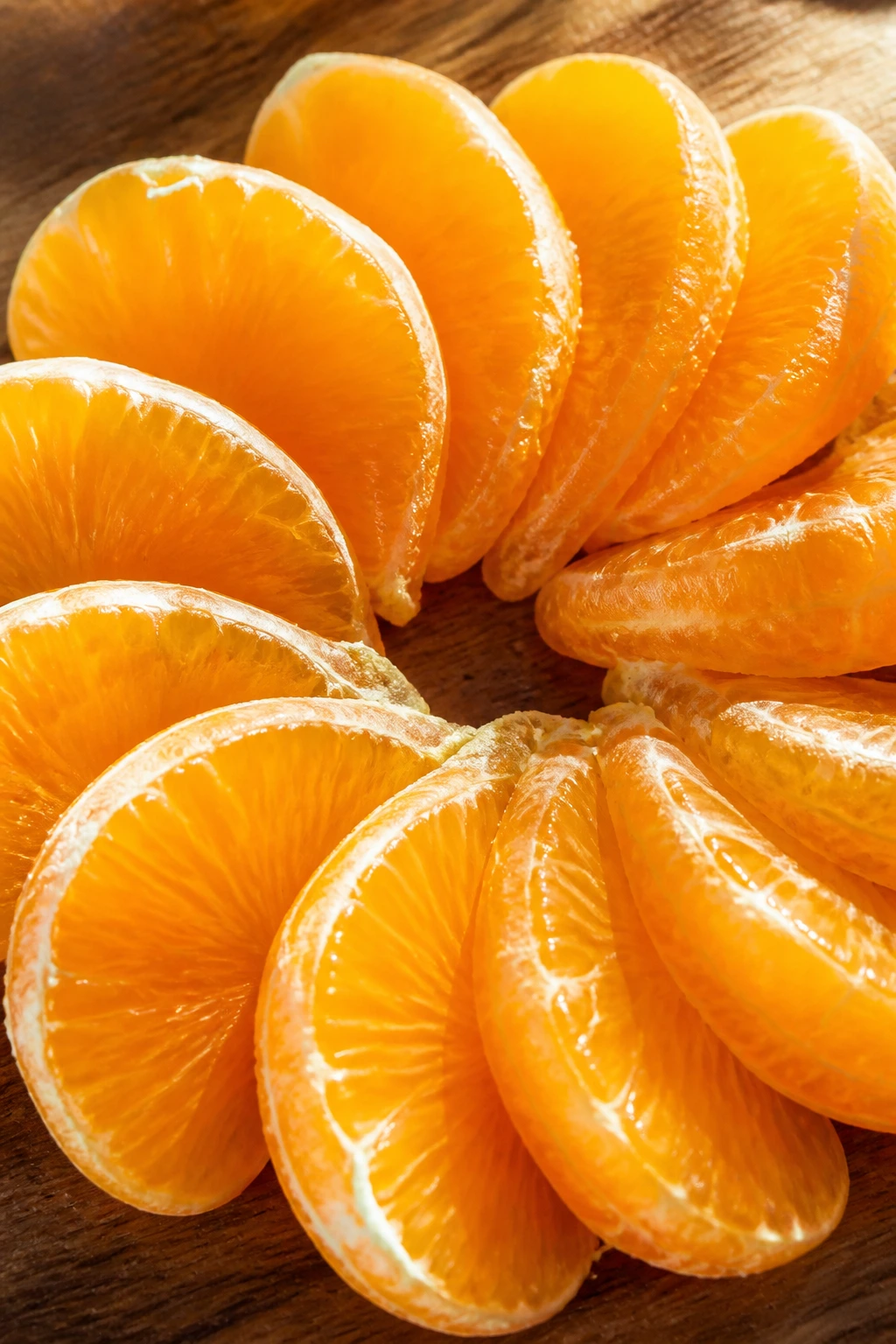 Orange Power: Are Oranges Good For Weight Loss? 3 Orange segments arranged in a circle on wood, highlighting fiber and vitamin C for a weight loss diet.