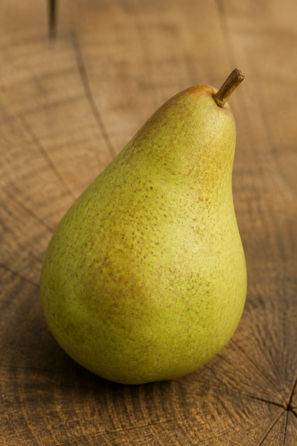 Anjou Vs Bartlett: The Ultimate Pear Comparison 7 Single pear on wooden surface highlighting texture