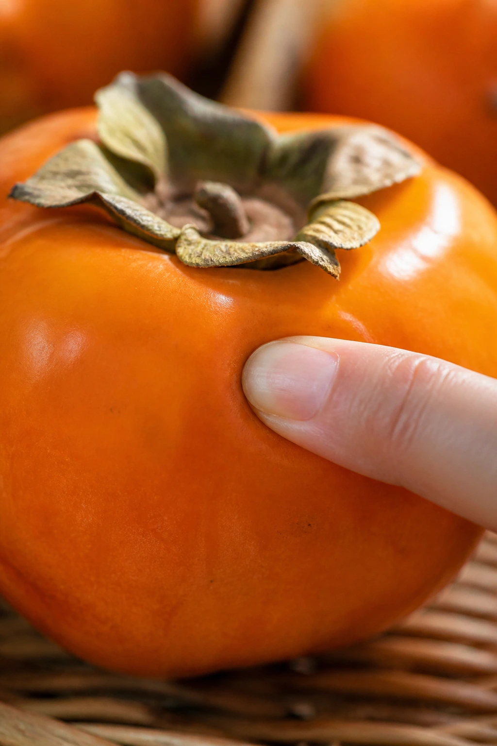 How To Remove Astringency from Persimmon Fruits 3 Persimmon being tested for ripeness by pressing with a finger