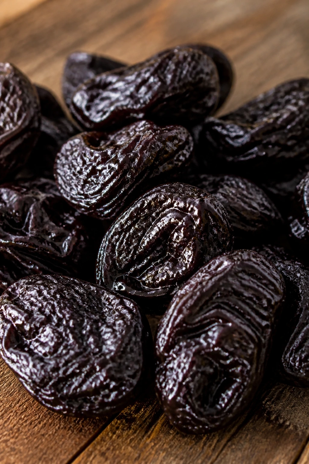 Close-up of prunes filling frame on rustic wooden kitchen surface