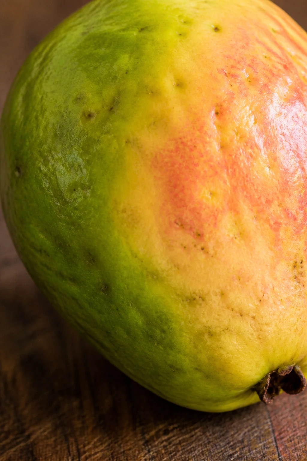 How Can You Tell If A Guava Is Ripe: Indicators to Look For 1 Close-up of ripe guava skin turning yellow with pink spots on a wooden board