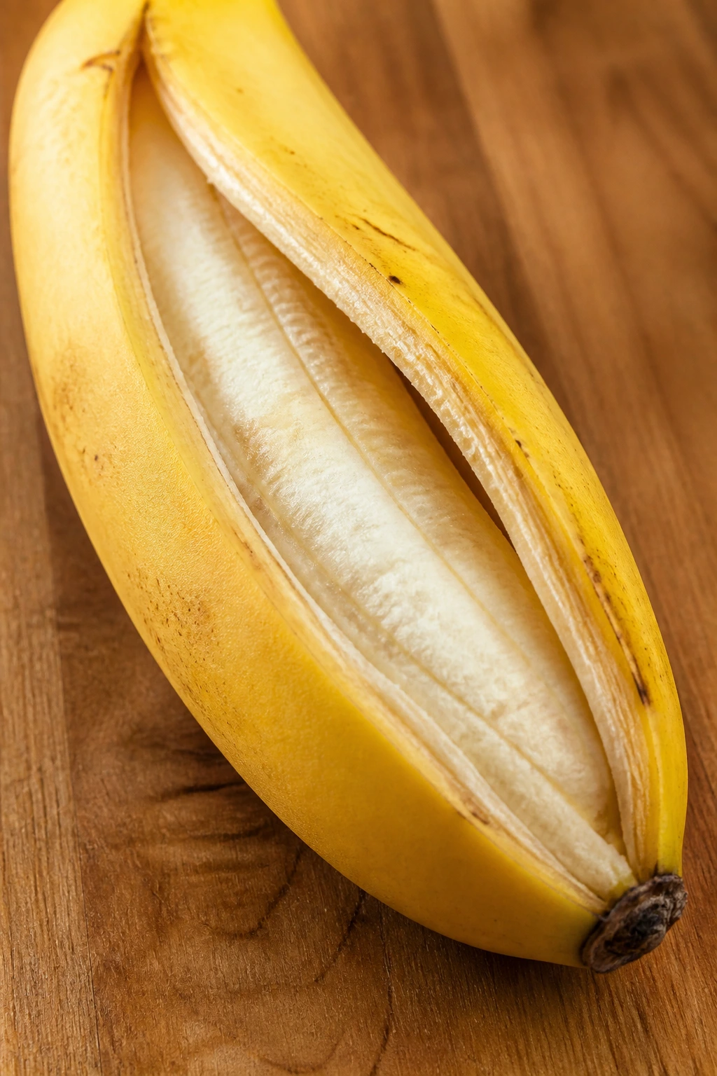 Are Bananas With Split Skins Safe To Eat? 4 Split banana with interior exposed on wooden surface.