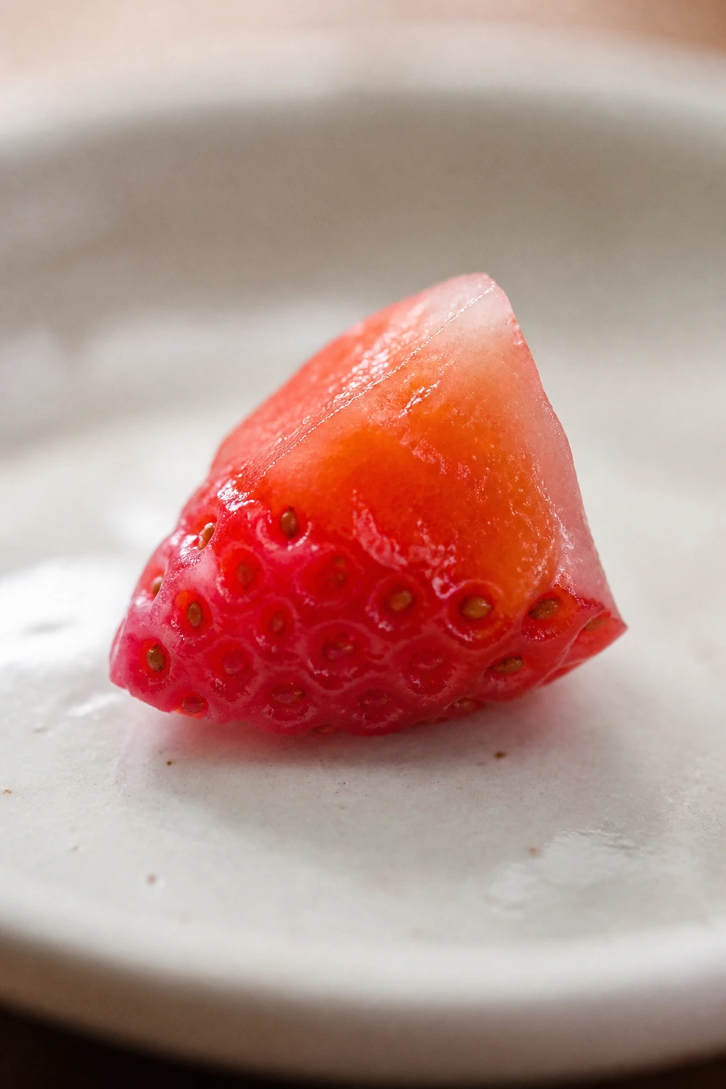 Tiny strawberry segment filling the frame on a light plate