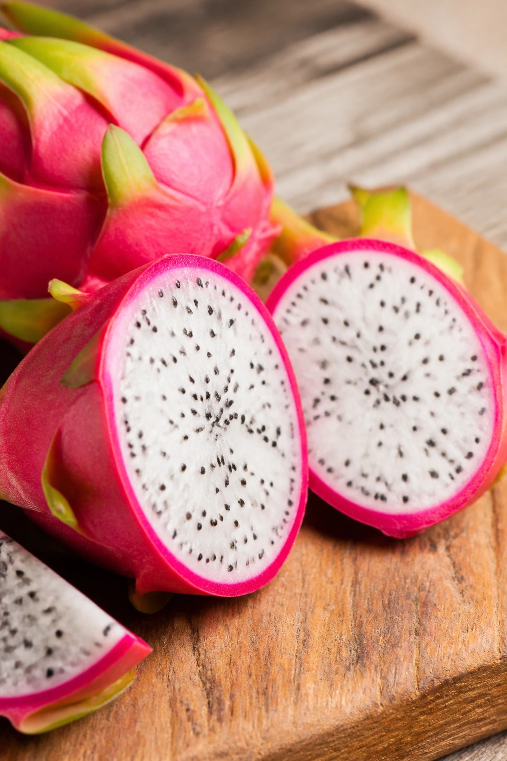 Dragon fruit cut open with seeds on a wooden surface