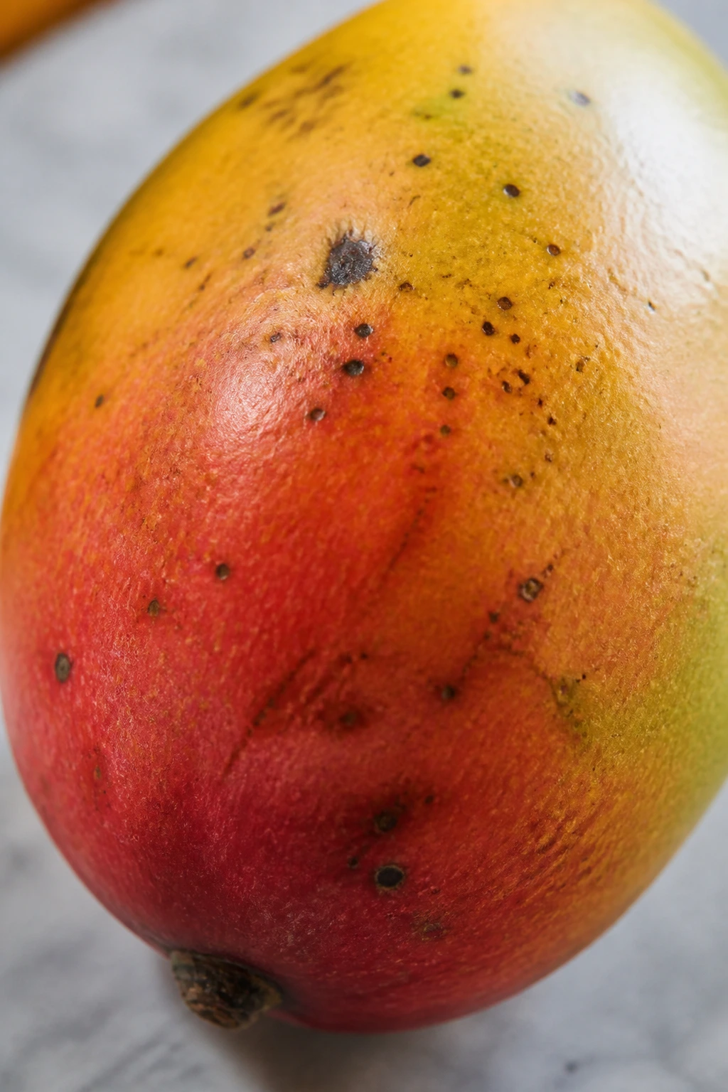 Mango with blemishes on a kitchen surface